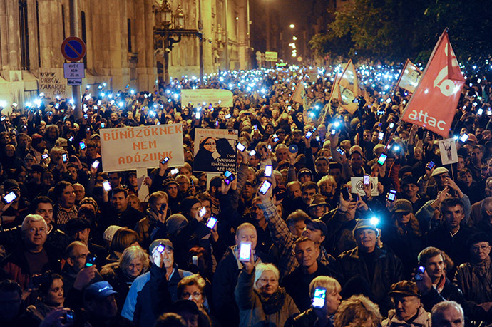 Hungarian citizens lift their mobile phones to protest against the goverment's new tax plan for the introduction of the internet tax next year in Budapest downtown on October 26, 2014.